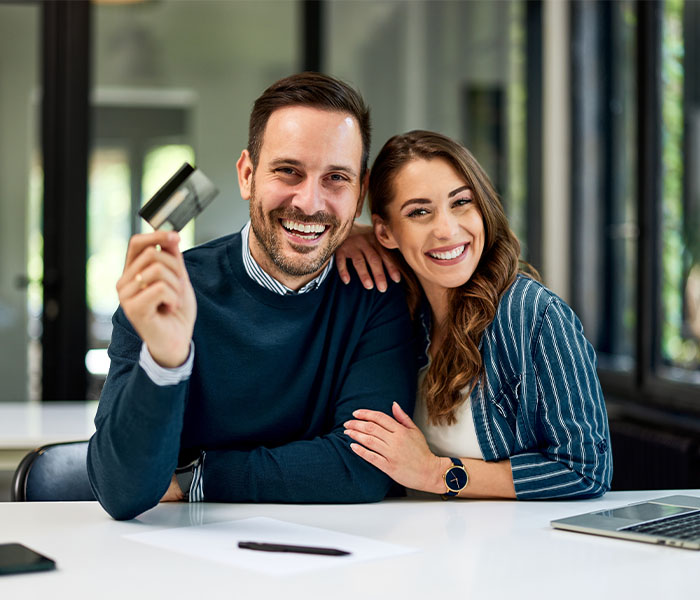 couple smiling holding a credit card together